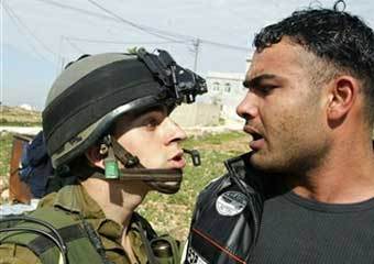 Израильский солдат беседует с палестинцем в Рамалле, фото AFP