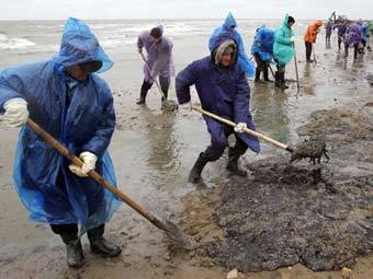 Добровольцы очищают берег Черного моря от мазута. Архивное фото AFP